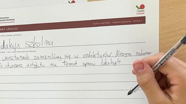 Ręka ucznia wypełnia stronę działu Sprawy lokalne: tytuł „Redakcja szkolna” i tekst „Na warsztatach zamieniliśmy się w redaktorów”